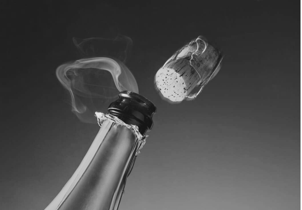 A champagne bottle gently releases its cork a gentle plume of smoke